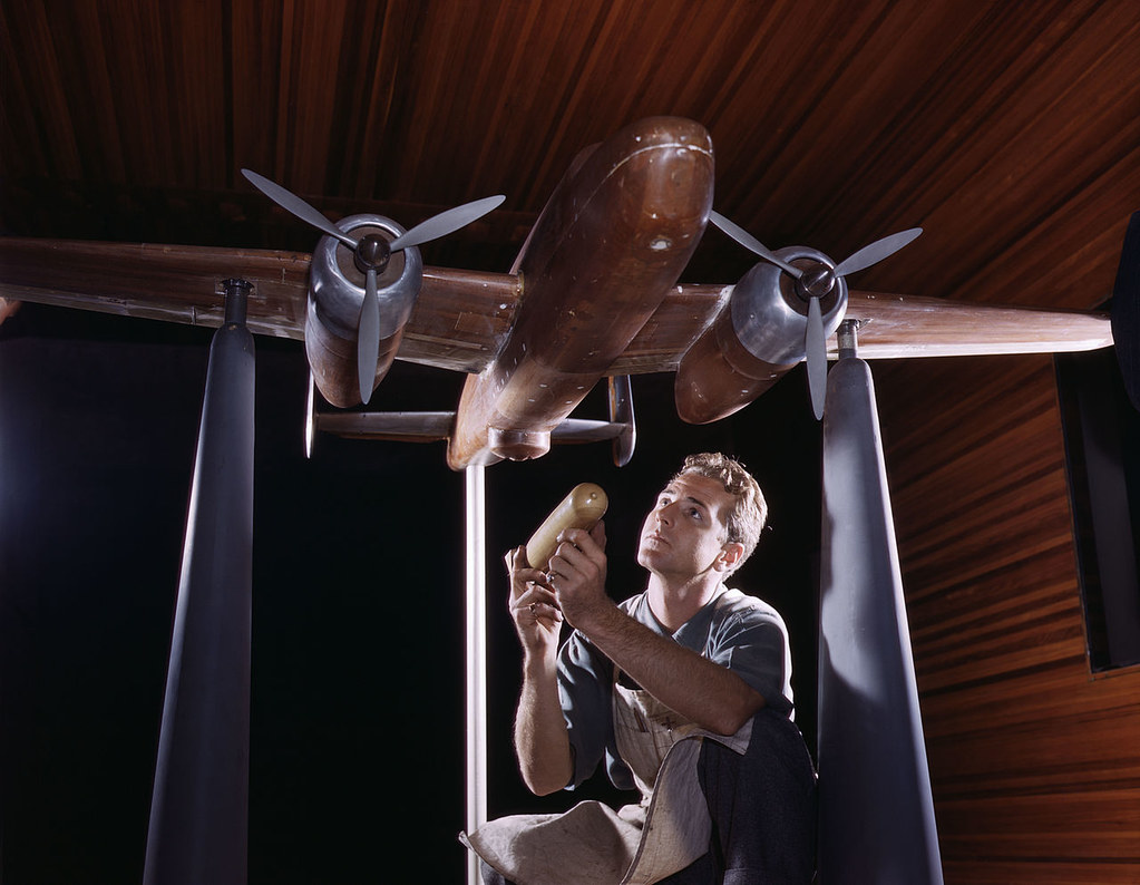 An experimental scale model of the B-25 plane is prepared for wind tunnel tests in the plant of the North American Aviation, Inc, Inglewood, Calif, The model maker holds an exact miniature reproduction of the type of bomb the plane will carry.