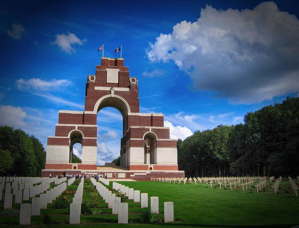 Graves in the Thiepval Anglo-French Cemetery, seen with the Thiepval Memorial to the Missing of the Somme, Thiepval, France.